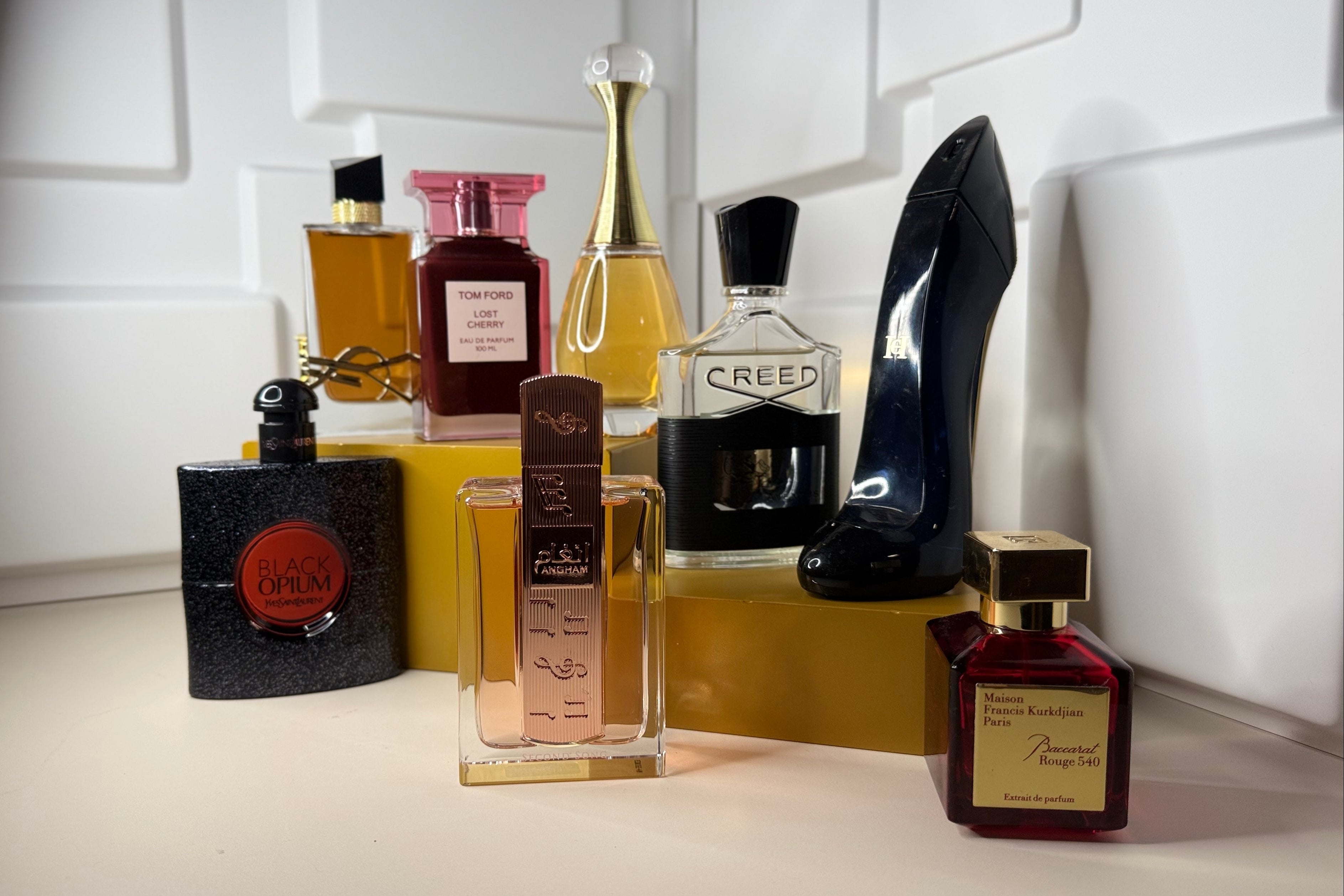 Collection of perfume bottles on a white surface with a high heel shoe in the background.